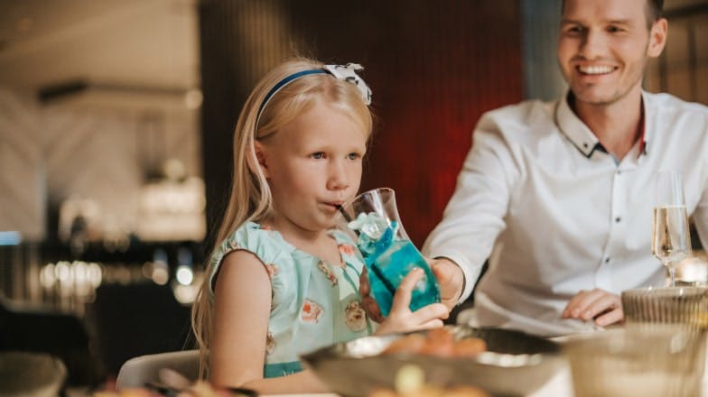 Laps laua taga laste kokteili joomas